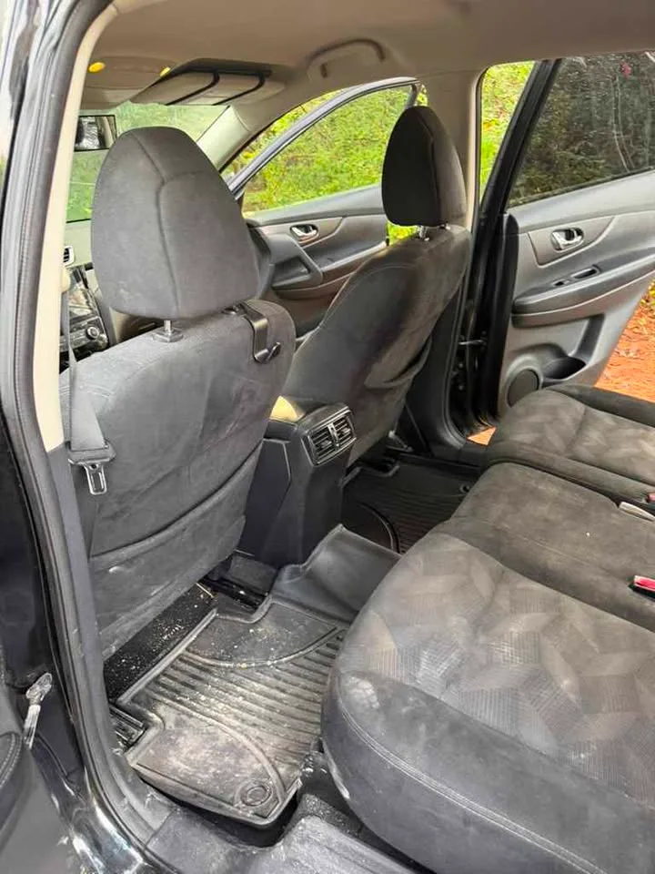 A back seat before detailing — dirt and crumbs across the floor mat
